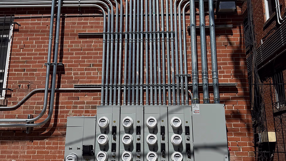 Code-compliant commercial electrical meter bank
 with neatly bent rigid conduit runs on a brick building exterior