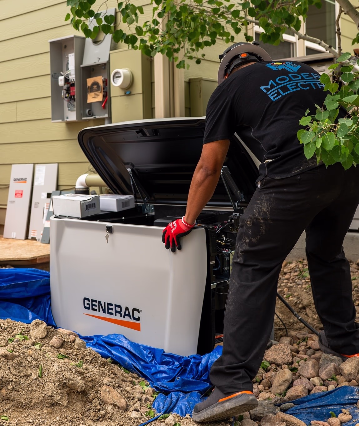 Modern Electric electrician installing a Generac standby generator and transfer switch outside a home