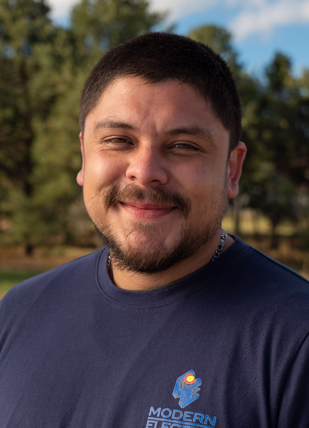 Faustin, Lead RW Electrician at Modern Electric, outdoor headshot in a navy company T-shirt