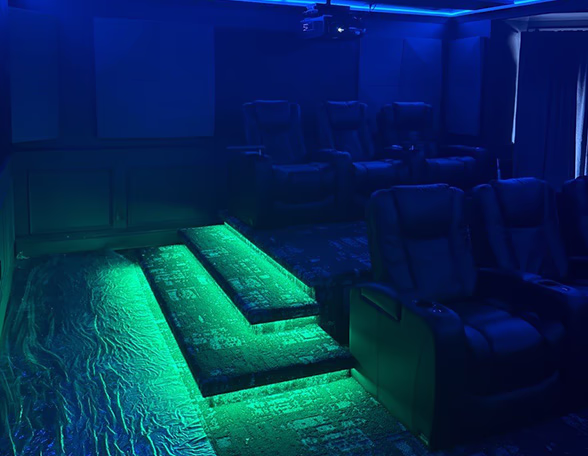 Home theater wired by Modern Electric with green LED step and floor lighting, a projector, and reclining seats