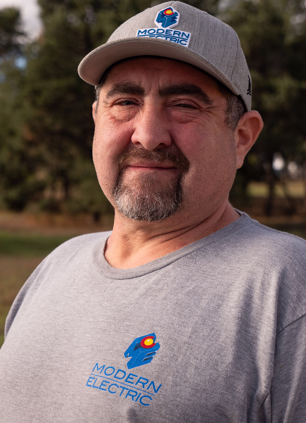Jerol, Service Electrician at Modern Electric, outdoor headshot in a gray company cap and T-shirt